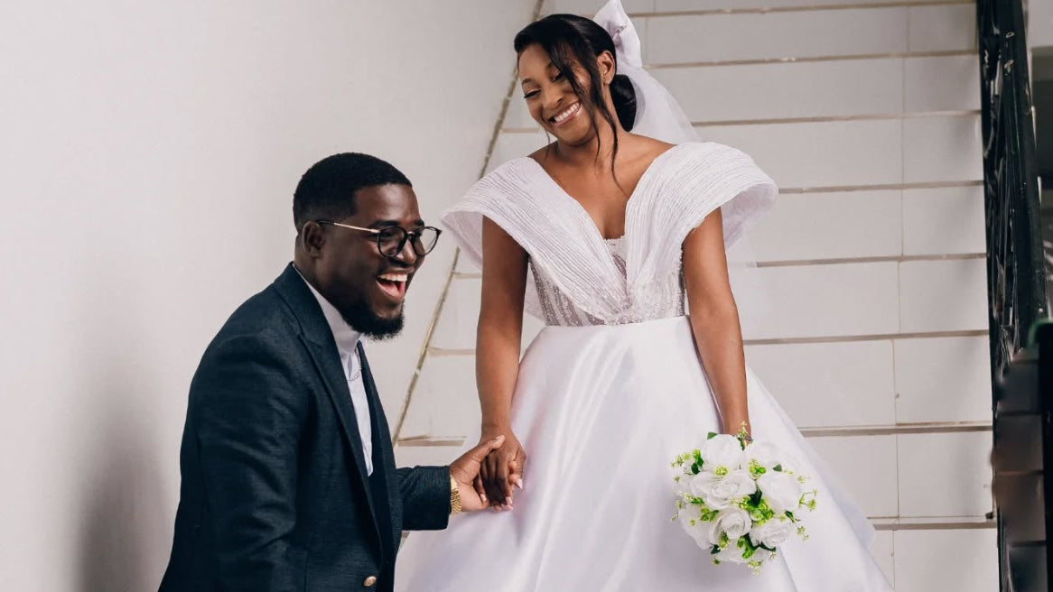 Man in a suit and woman in a white dress sitting on a staircase.